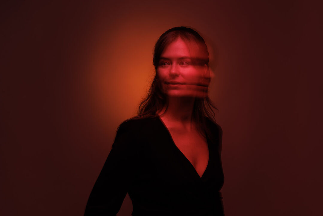 Annemijn Rijk voor een rode achtergrond met een wazig gezicht.