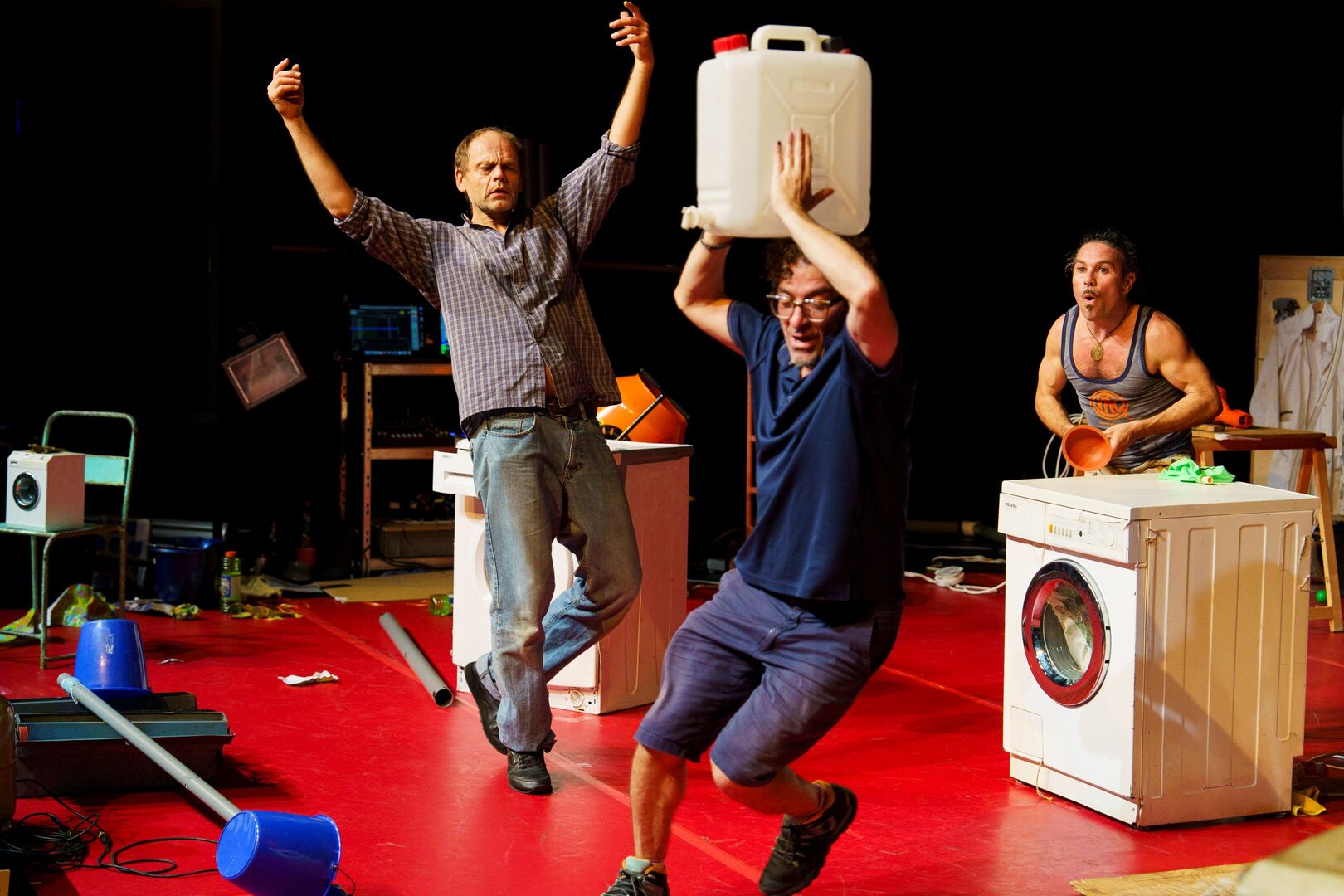 Drie spelers op het toneel een met een jerrycan boven zijn hoofd