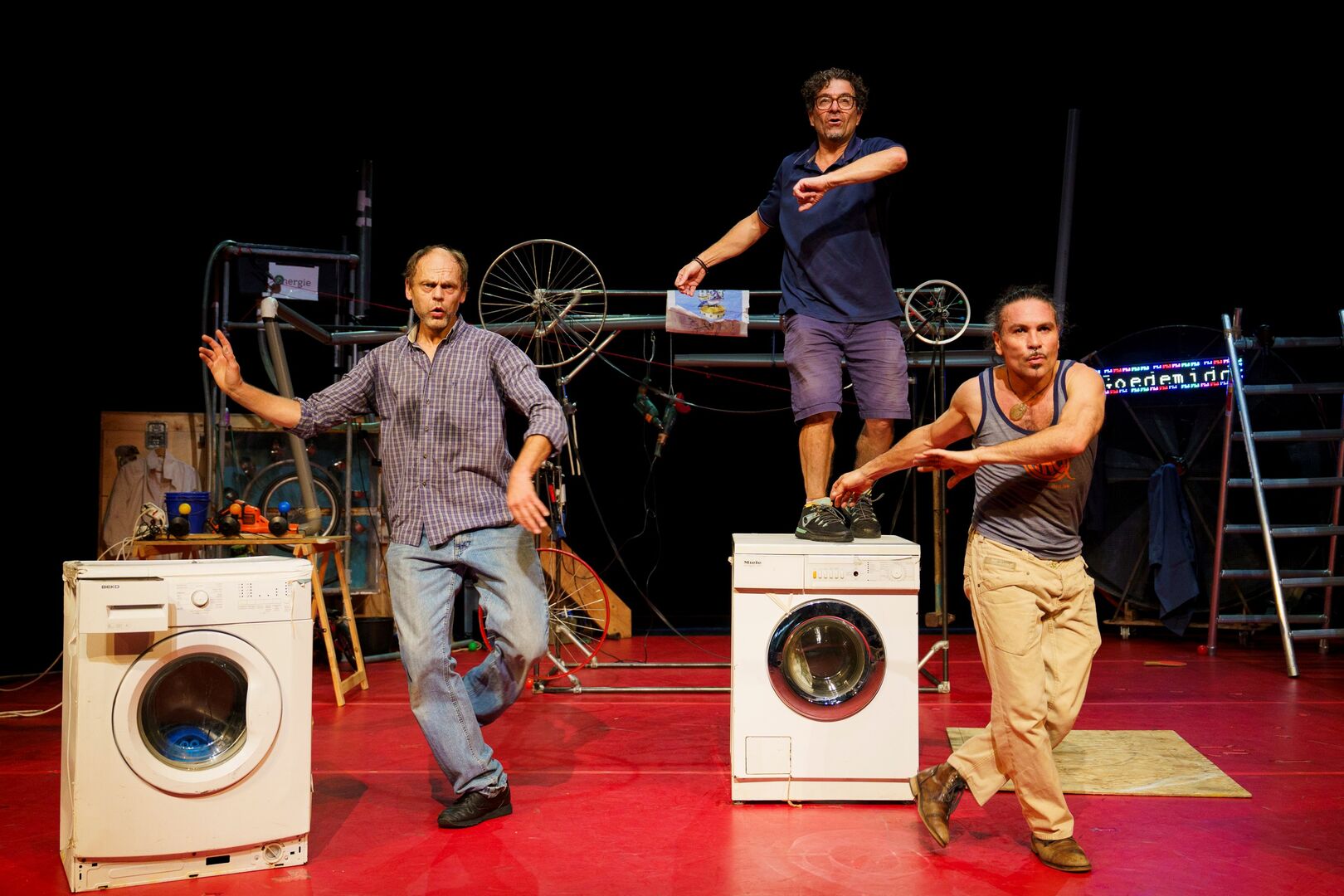 drie mannen dansen op het toneel en wasmachines