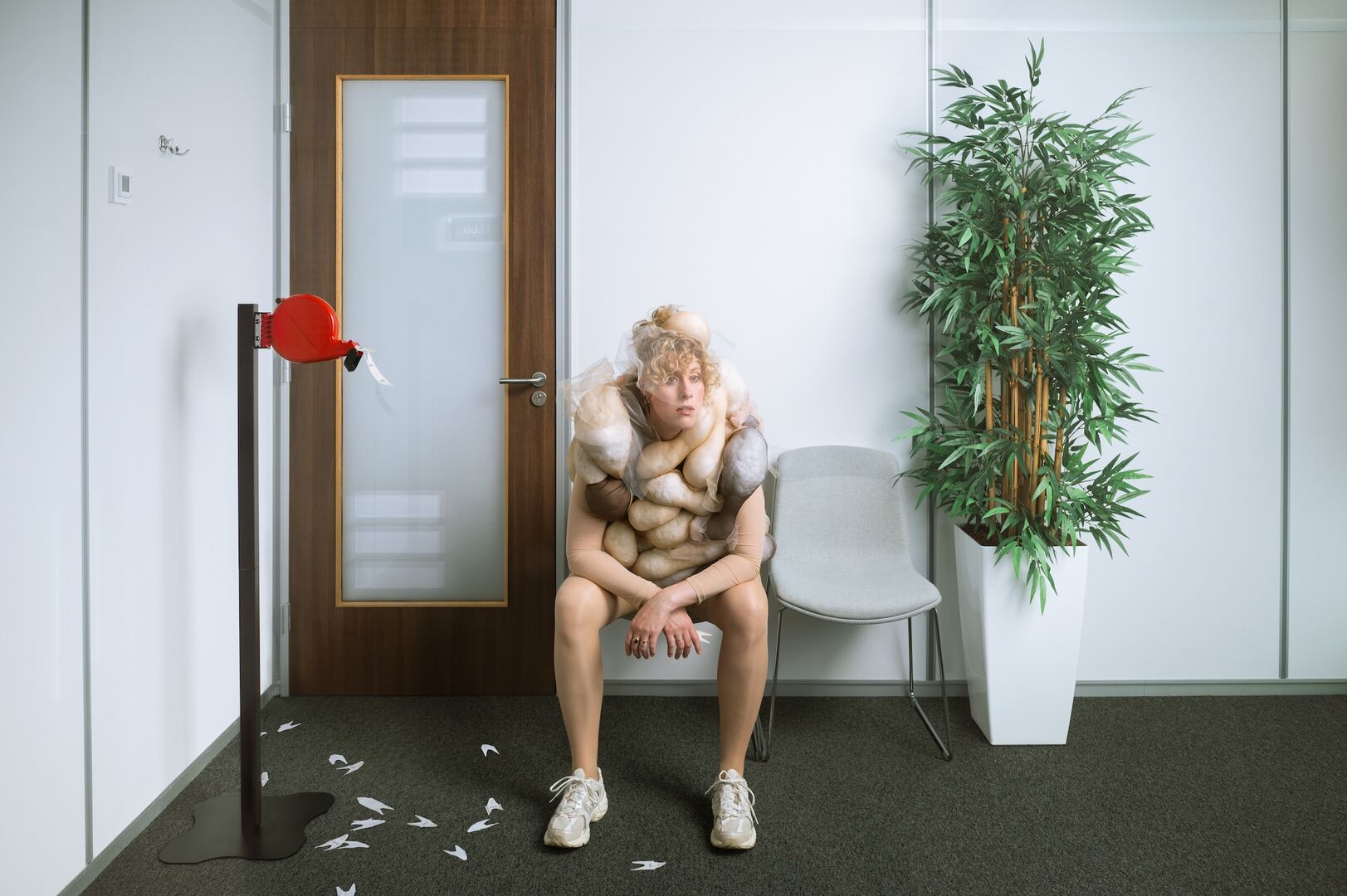 Vrouw zit in de wachtkamer met allemaal textiel bulten aan haar vast