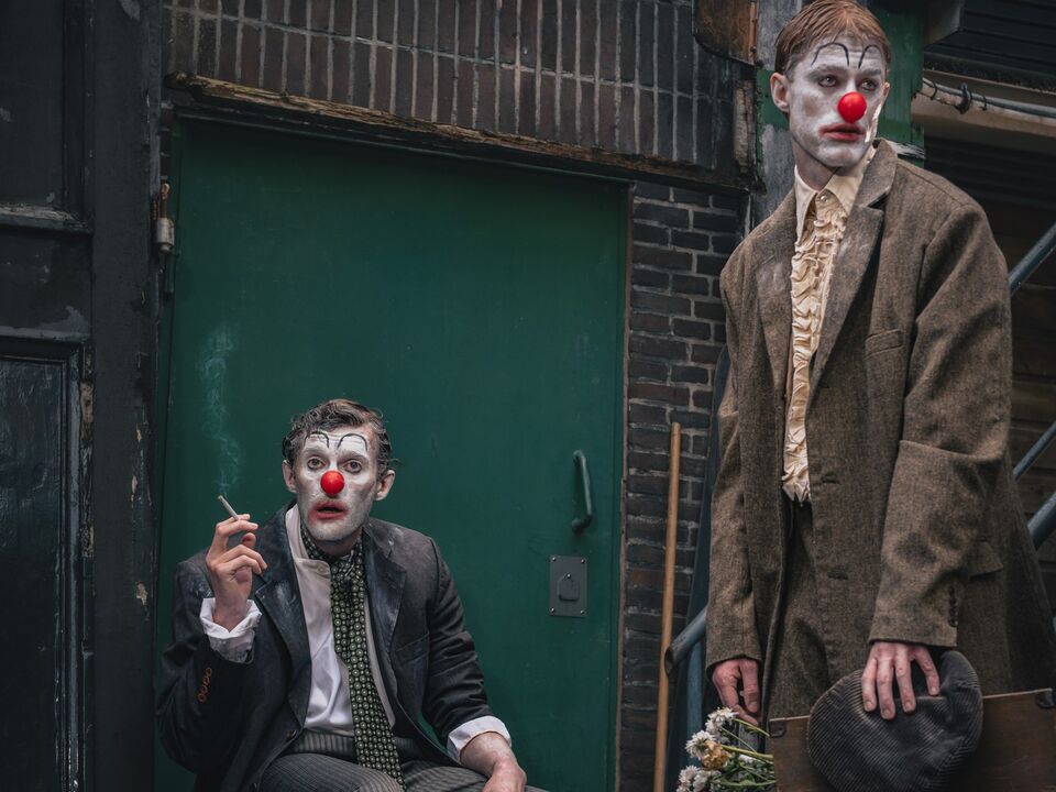 Twee sombere clowns in een grauwe steeg 