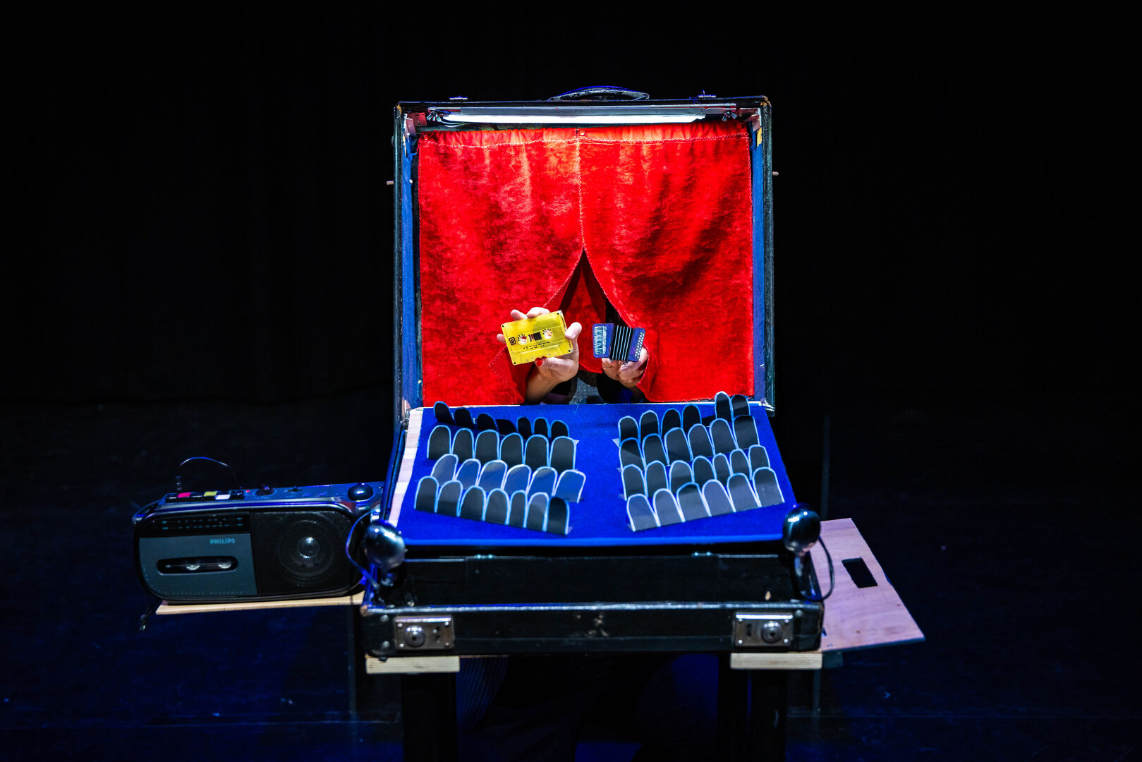 Een casettebandje en accordeon staan op een geknutseld toneel