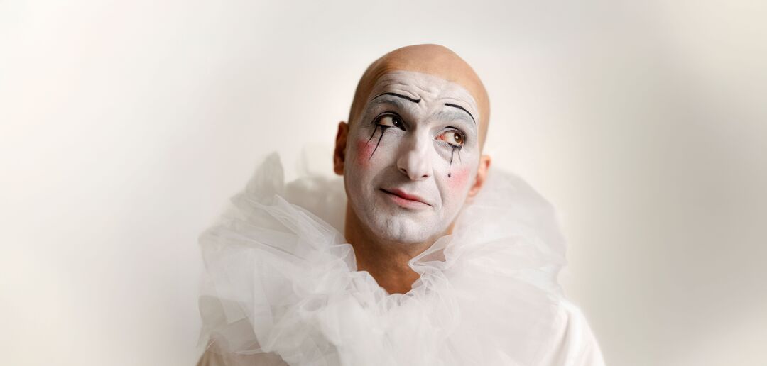 Een kale clown gekleed in wit