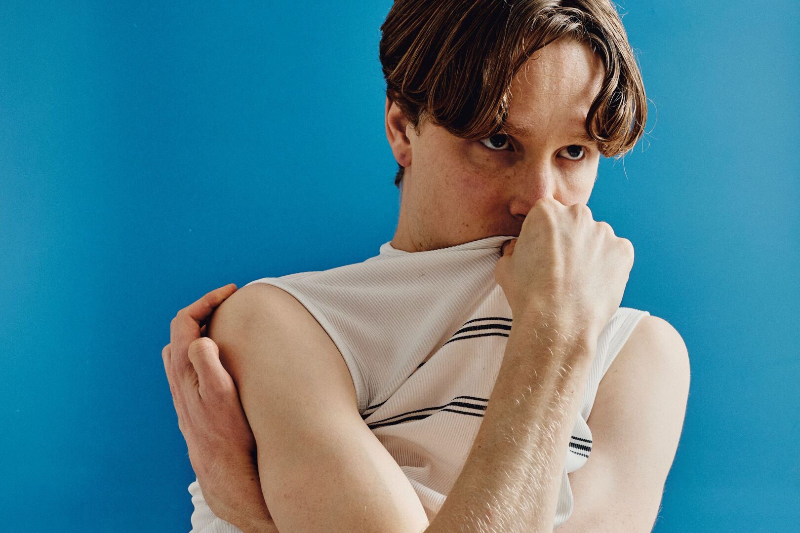 Jongen trekt zijn shirt half over zijn hoofd en kijkt weg