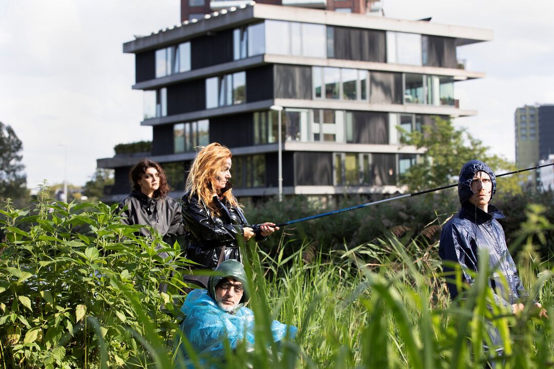 vier mensen staan in een veld met hoog gras