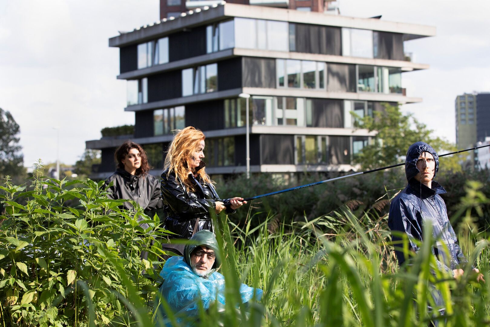 vier mensen staan in een veld met hoog gras