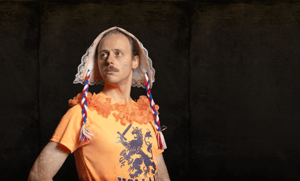 Beeld van een man in oranje kleding met een traditioneel nederlands hoedje op zijn hoofd